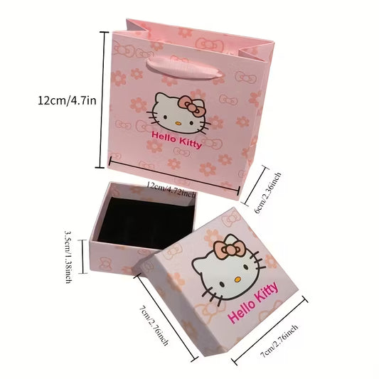 Söpö vaaleanpunainen Hello Kitty -lahjarasia ja siihen sopiva kantokassi asetettuna tasolle. Rasia on avattu osoittamaan, että se on valmis korua varten.