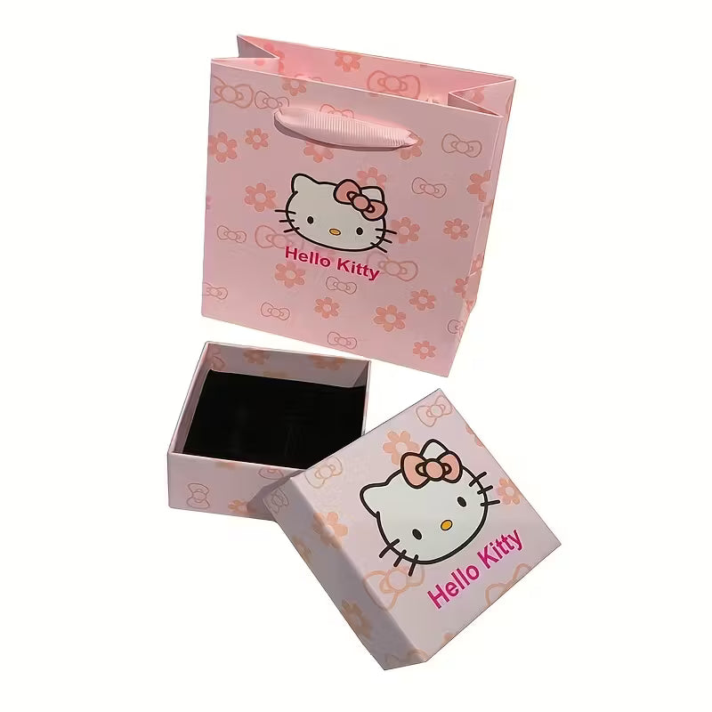 Söpö vaaleanpunainen Hello Kitty -lahjarasia ja siihen sopiva kantokassi asetettuna tasolle. Rasia on avattu osoittamaan, että se on valmis korua varten.