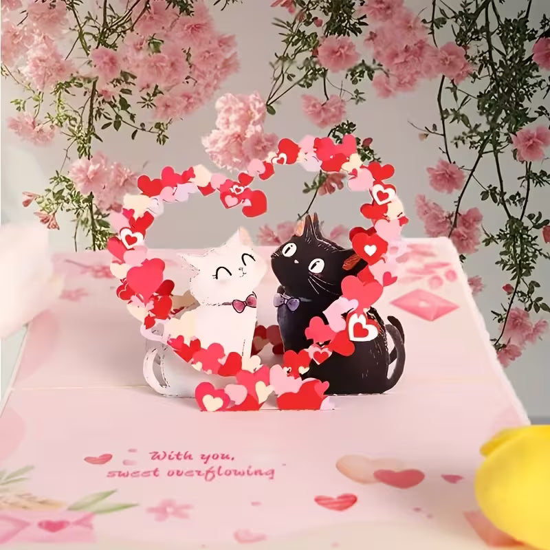 Avattu vaaleanpunainen 3D pop-up -kortti, jossa musta ja valkoinen kissa istuvat sydänkaaren alla ja teksti 'With you, sweet overflowing