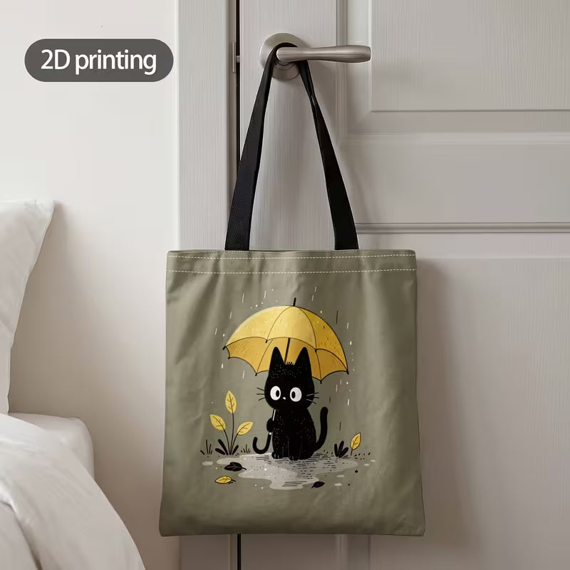 Tuotekuva salvianvihreästä kangaskassista, jossa on 2D-printtikuviointi mustasta kissasta keltaisen sateenvarjon alla sadepäivänä.