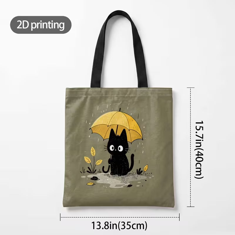 Tuotekuva salvianvihreästä kangaskassista, jossa on 2D-printtikuviointi mustasta kissasta keltaisen sateenvarjon alla sadepäivänä.