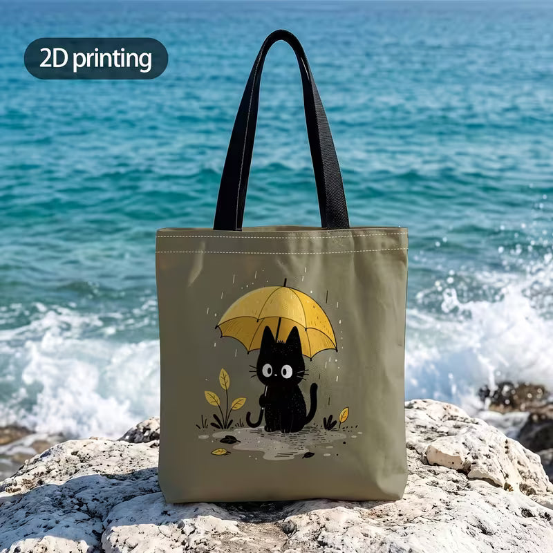 Tuotekuva salvianvihreästä kangaskassista, jossa on 2D-printtikuviointi mustasta kissasta keltaisen sateenvarjon alla sadepäivänä.
