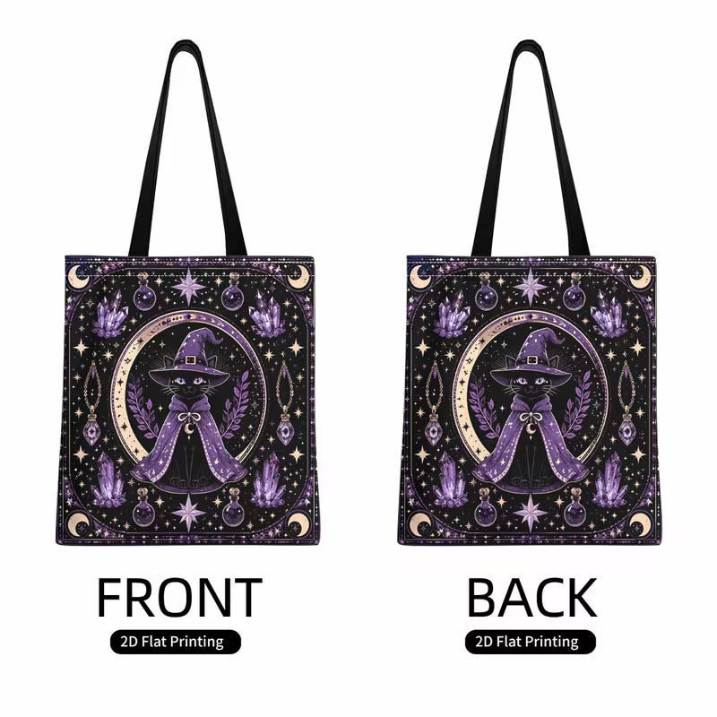 Tuotekuva tummasävyisestä kangaskassista, jossa on 2D-printti noidanhattuun pukeutuneesta mustasta kissasta, kuu- ja kristallikuvioista sekä mustat kantohihnat.   