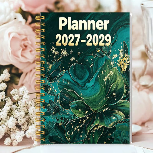 Tuotekuva Planner 2027-2029 -kalenterista, jossa on tummanvihreä fluid art -tyylinen kukkakansi kultahippusilla ja kultainen kierresidonta.   