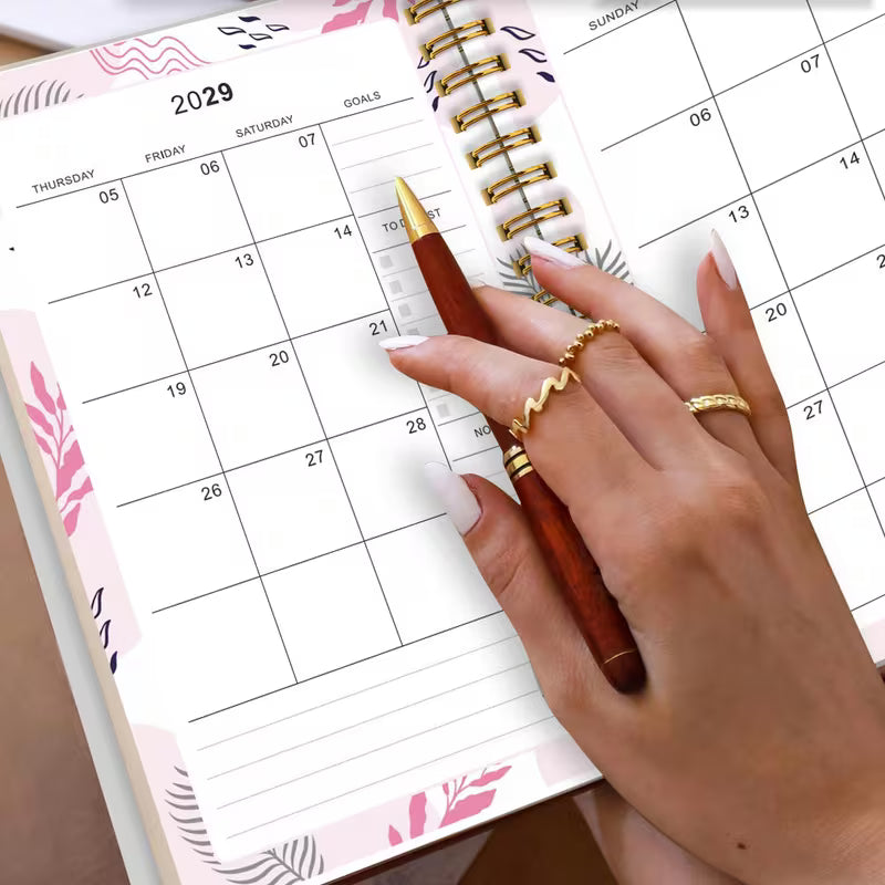Tuotekuva Planner 2027-2029 -kalenterista, jossa on tummanvihreä fluid art -tyylinen kukkakansi kultahippusilla ja kultainen kierresidonta.   