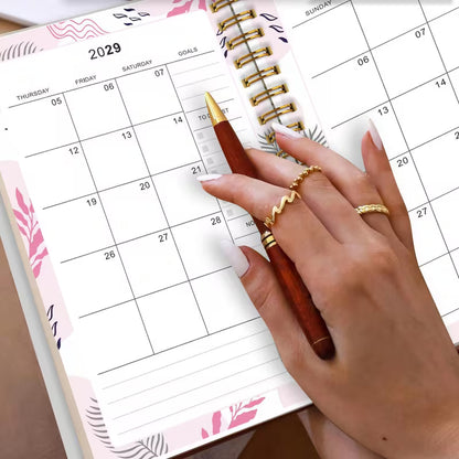 Tuotekuva Planner 2027-2029 -kalenterista, jossa on tummanvihreä fluid art -tyylinen kukkakansi kultahippusilla ja kultainen kierresidonta.   