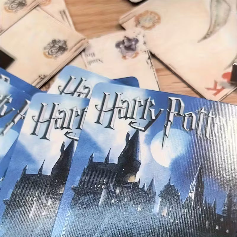 Harry Potter -pelikorttipakka ja esimerkkikortteja, joissa on kuvituksena Kelmien kartta, Kolmivelhopokaali ja Tylypahkan linna.