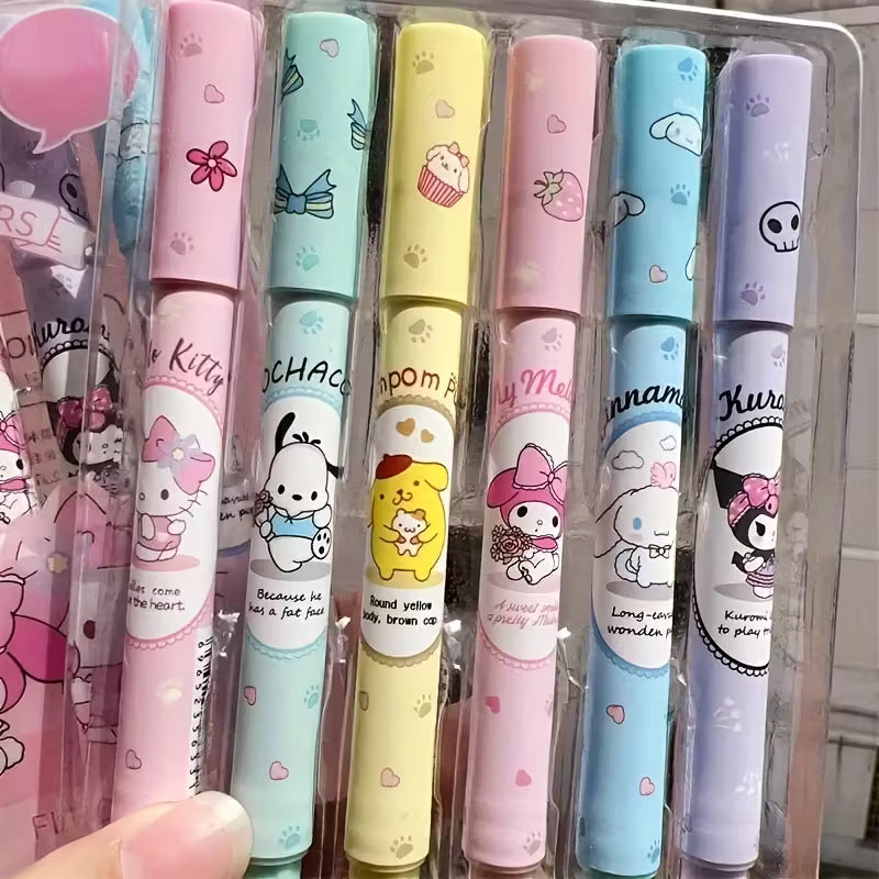 Kuusi pastellinväristä korostuskynää, joissa on Hello Kitty- ja Sanrio-hahmojen kuvia. Kynät on aseteltu avatun muistikirjan viereen valkoisella pöydällä