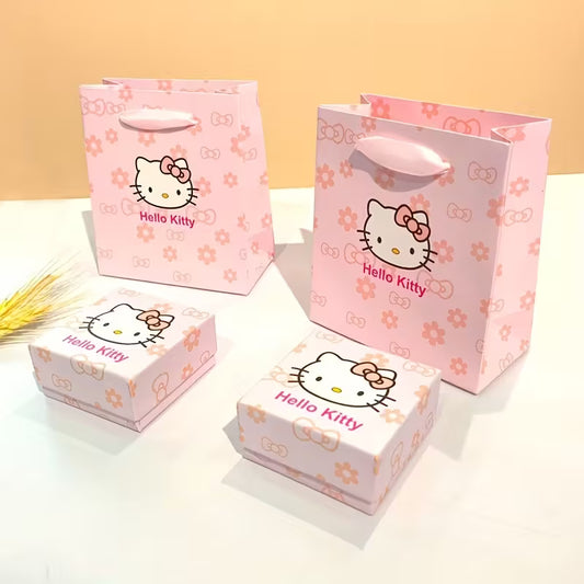 Söpö vaaleanpunainen Hello Kitty -lahjarasia ja siihen sopiva kantokassi asetettuna tasolle. Rasia on avattu osoittamaan, että se on valmis korua varten.