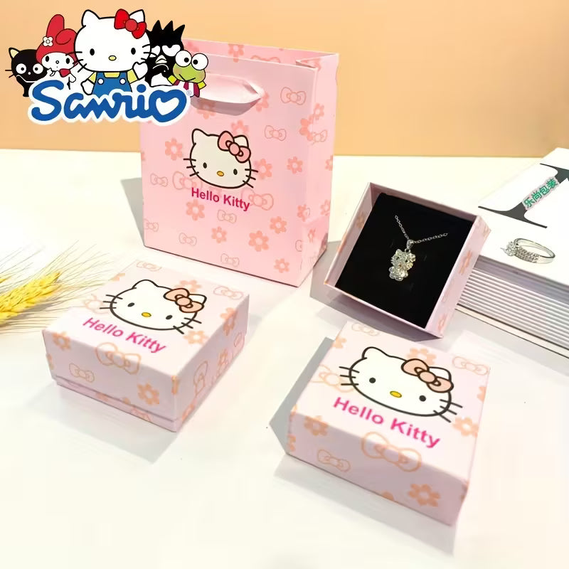 Söpö vaaleanpunainen Hello Kitty -lahjarasia ja siihen sopiva kantokassi asetettuna tasolle. Rasia on avattu osoittamaan, että se on valmis korua varten.