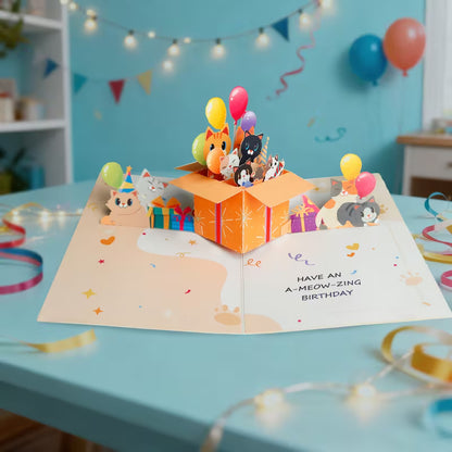 Avattu 3D pop-up -syntymäpäiväkortti, jossa oranssista lahjalaatikosta kurkistaa useita erivärisiä kissoja ja ilmapalloja sekä teksti Have an A-meow-zing birthday.