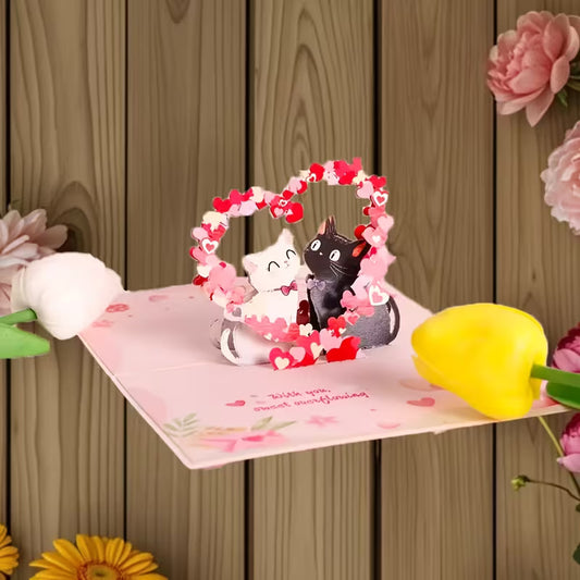 Avattu vaaleanpunainen 3D pop-up -kortti, jossa musta ja valkoinen kissa istuvat sydänkaaren alla ja teksti 'With you, sweet overflowing