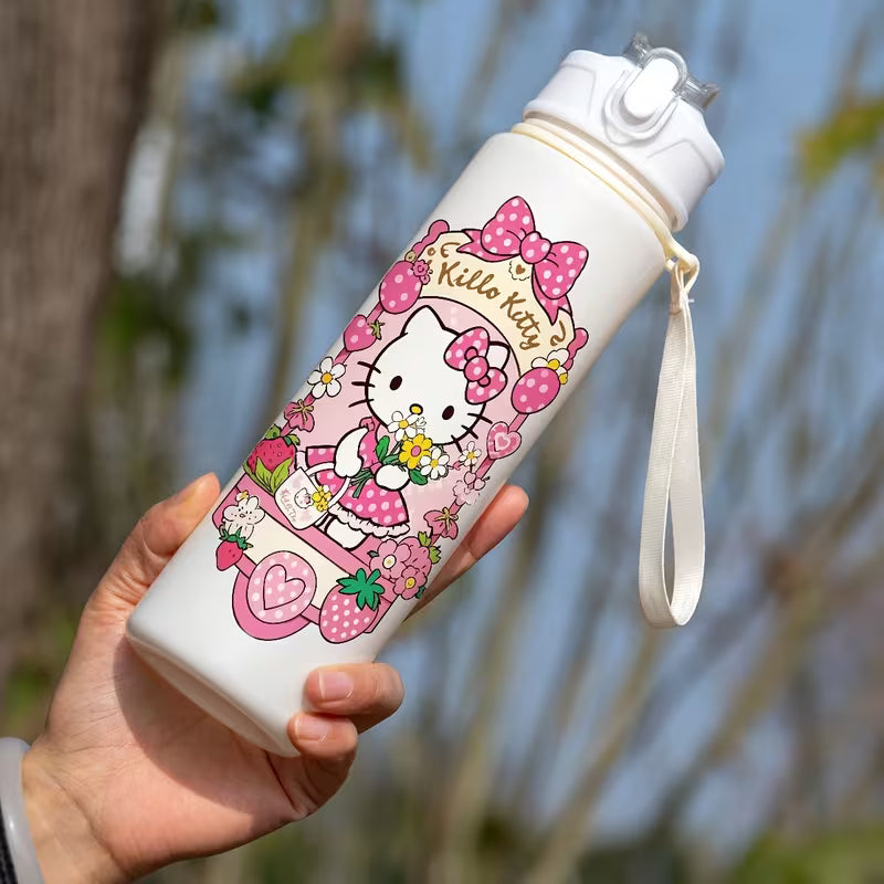 Käsi pitelee suloista pinkkiä Hello Kitty -juomapulloa, jossa on sisäänrakennettu pilli, aurinkoisessa puutarhassa.