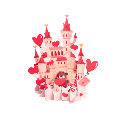 Avattu 3D pop-up -kortti, josta nousee näyttävä vaaleanpunainen linna täynnä sydämiä ja suloinen nallekarhu, kuvattuna vaaleanpunaisella alustalla.