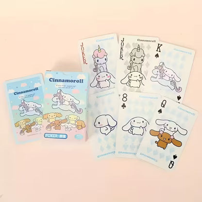 Levitettyjä Cinnamoroll-pelikortteja ja alkuperäinen korttipakka, joissa on suloista hahmokuvitusta pastelliväreissä.