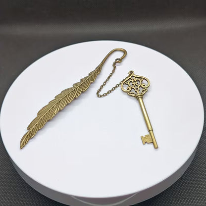 Elegantti metallinen höyhenen muotoinen kirjanmerkki, jossa on hienostuneita kaiverruksia, lepäämässä vanhan nahkakantisen kirjan sivujen päällä.