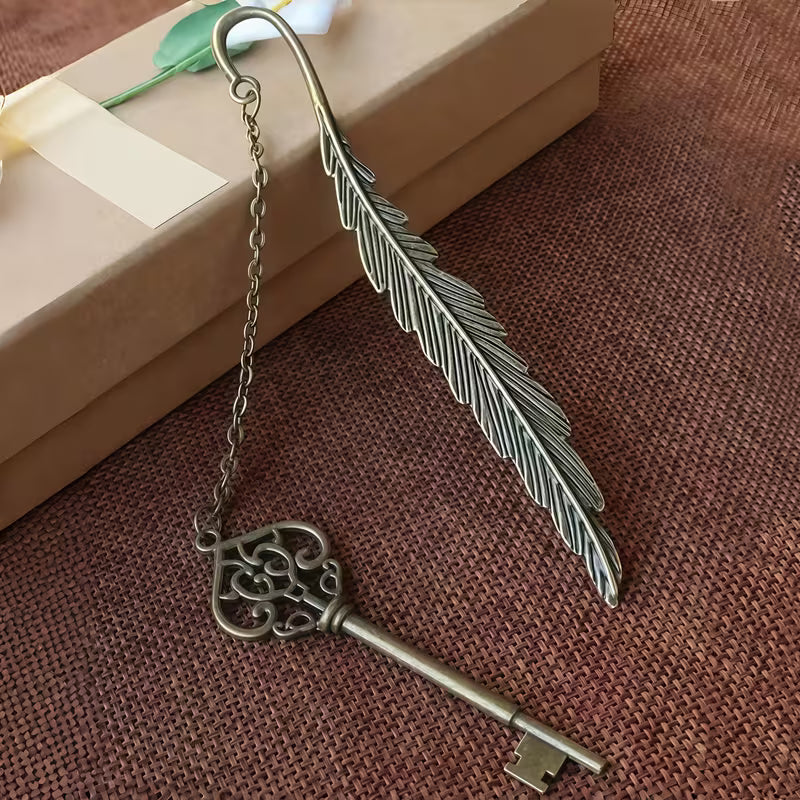 Elegantti metallinen höyhenen muotoinen kirjanmerkki, jossa on hienostuneita kaiverruksia, lepäämässä vanhan nahkakantisen kirjan sivujen päällä.