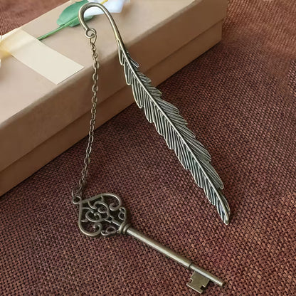 Elegantti metallinen höyhenen muotoinen kirjanmerkki, jossa on hienostuneita kaiverruksia, lepäämässä vanhan nahkakantisen kirjan sivujen päällä.