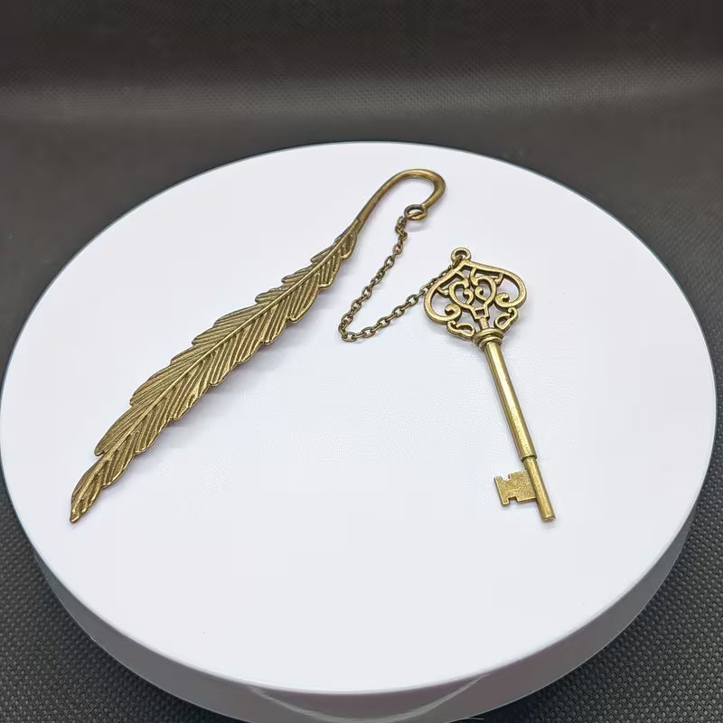 Elegantti metallinen höyhenen muotoinen kirjanmerkki, jossa on hienostuneita kaiverruksia, lepäämässä vanhan nahkakantisen kirjan sivujen päällä.