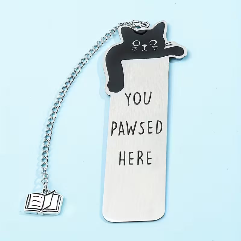 Metallinen kirjanmerkki, jossa on musta kissa, teksti 'You pawsed here' ja ketjussa roikkuva pieni kirja-riipus mittoineen